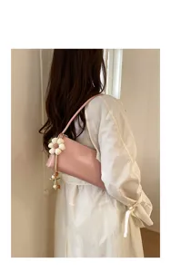 Detailed view of trendy pink underarm shoulder bag with delicate flower charm accessory.
