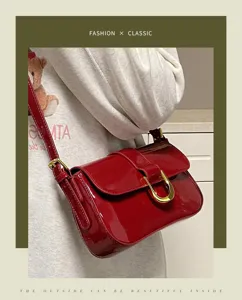 Detailed view of the elegant red patent leather shoulder bag with chic horseshoe buckle.