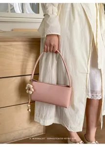 Pink leather underarm shoulder bag detail showcasing floral charm and minimalist retro vibe.