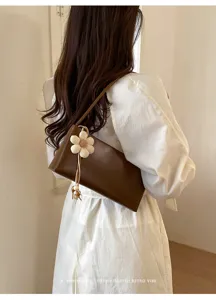 Retro brown PU leather shoulder bag for women, elegant underarm bag with cute flower pendant.