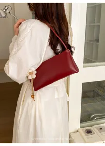 Dark red PU leather shoulder bag detail, stylish baguette handbag with floral pendant.