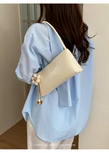 Detailed view of minimal white PU leather shoulder bag with cute flower charm accessory.