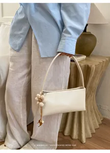 Close-up detail of the elegant white leather underarm shoulder bag with cute flower charm.