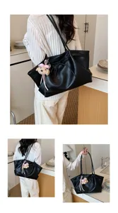 Detail view of black faux leather tote bag with cute bear pendant in modern setting.