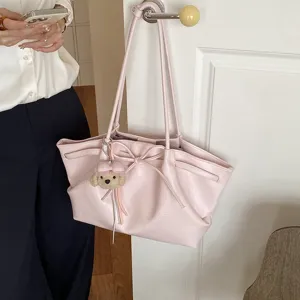 Close-up of a stylish soft pink tote bag featuring a cute bow detail and a plush puppy pendant.