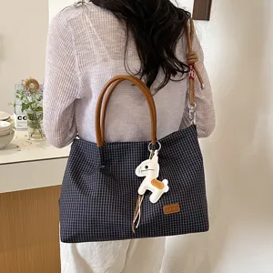 Vue détaillée du sac cabas à carreaux élégant avec poignées marron et charm cheval.