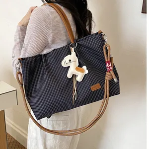 Vue détaillée du sac cabas à carreaux avec charm de cheval en cuir élégant et bretelles robustes.