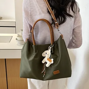 Sac cabas vert olive pour femme avec poignées marron et pendentif cheval chic.