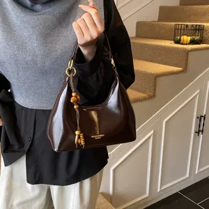 Elegant brown patent leather underarm bag with wooden bead tassel, vintage style shoulder bag.