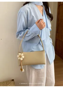 Minimalist PU leather shoulder bag for women, retro underarm bag with cute flower charm.