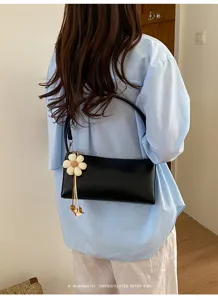 Minimalist black PU leather underarm shoulder bag with cute floral pendant for women.