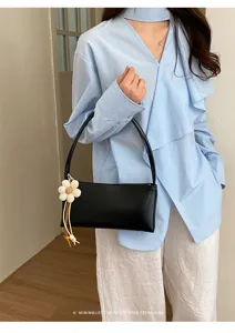 Minimalist black PU shoulder bag with cute flower charm, elegant underarm tote for women.