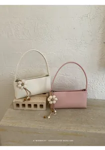 Detail view of minimalist retro PU shoulder bags with cute flower charms on textured background.