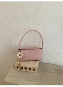 Minimalist pink PU shoulder bag with flower pendant, retro baguette style for daily chic look.