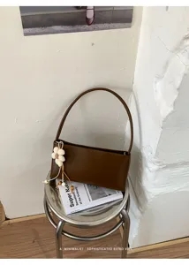 Detail view of brown PU shoulder bag featuring floral charm and minimalist retro aesthetic.