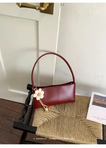 Close-up detail of vintage burgundy PU shoulder bag with cute flower charm and rigid structured design.
