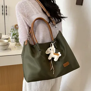 Vue détaillée d'un sac cabas vert élégant pour femme avec poignées marron et charm.