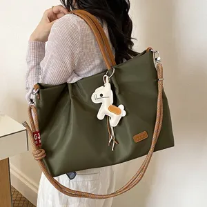 Vue détaillée du sac cabas pour femme vert foncé avec poignées marron et charm de cheval.