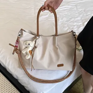 Vue détaillée de cabas beige avec poignées marron, bandoulière tressée et charm animal.
