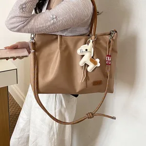 Vue détaillée du cabas beige décontracté avec bandoulière et charmant pendentif cheval.