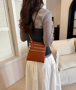 Detail view of stylish brown leather multi-zipper crossbody bag worn by model indoors.