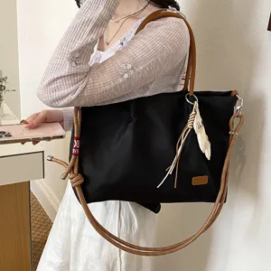 Vue detaillee du sac cabas en nylon avec poignees marron et sangle tressee style.