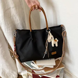 Sac cabas noir en nylon avec anses marron et charm cheval pour le travail et loisirs.