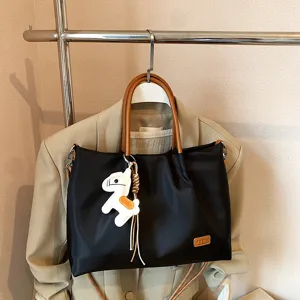 Élégant sac cabas noir en nylon avec anses, bandoulière et charmant pendentif cheval.