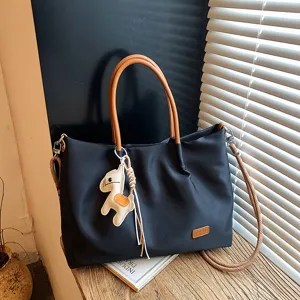 Détail du sac cabas en tissu noir avec poignées marron et charmant pendentif cheval.