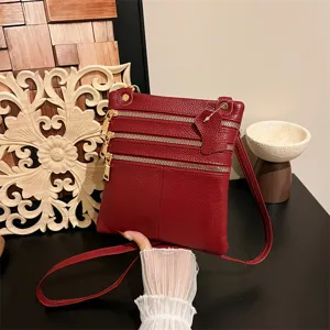 Detailed view of a red leather multi-zipper crossbody bag with gold tone hardware.