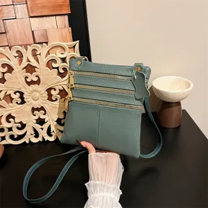 Women's green leather crossbody bag with multiple zip pockets and stylish hardware design.