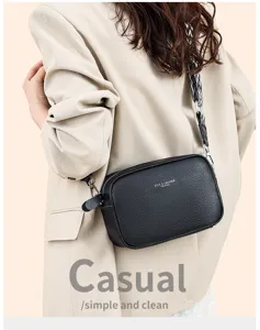 Detailed view of black leather crossbody bag with patterned wide strap and zipper closure.