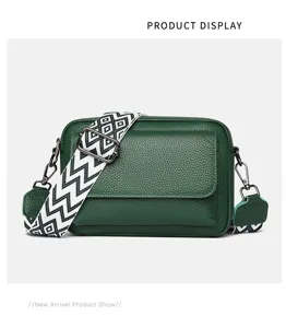 Detalle del bolso cruzado de piel verde con correa estampada y herrajes metálicos.