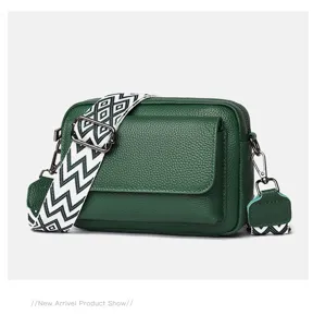 Detalle del bolso cruzado de cuero verde con una elegante correa geométrica y compartimentos.