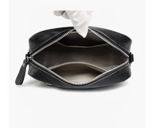 Interior detail view of black leather crossbody bag featuring multiple storage compartments and zippers.