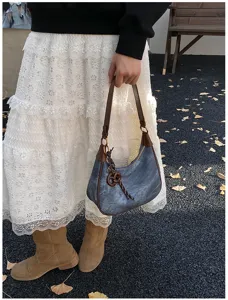 Borsa a tracolla in denim vintage con finiture in pelle marrone, vista dettagliata della lavorazione.