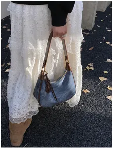 Vista dettagliata della borsa a spalla hobo retrò in denim da donna con bordatura marrone.