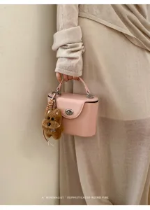 Pink structured box handbag detail, stylish top handle bag with cute fluffy dog keychain.