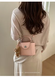 Stylish pink crossbody box bag with metal lock and cute bear charm for daily commute style.