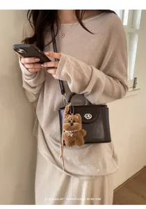 Detailed view of stylish brown leather crossbody box bag with cute plush bear charm pendant.