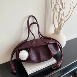 Detailed view of the dark red soft leather pleated cloud shoulder bag with white pompom charm.