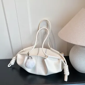Detail view of white soft leather cloud handbag, featuring knotted side straps and charm.