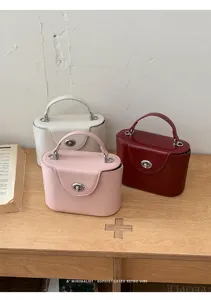 Elegant women's top-handle box handbag with secure turn-lock closure and retro design style.