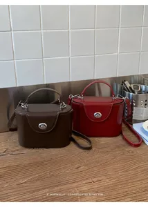 Minimalist retro style structured box handbag with turn-lock closure and chic top handle.