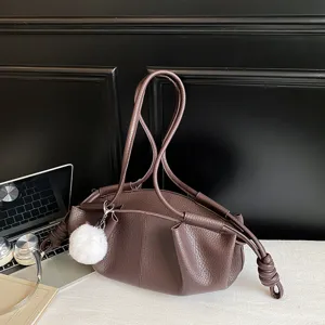 Brown leather shoulder bag with knotted straps and pom-pom charm for daily chic commute fashion.