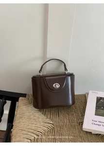 Detailed view of a retro dark brown top handle box bag with elegant metal turn-lock closure.