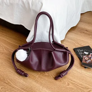 Burgundy soft leather shoulder bag with chic pleated cloud design and plush pompom charm detail.