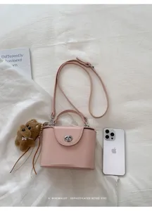 Pink structured box crossbody bag featuring top handle, metal turn-lock closure and cute bear charm.