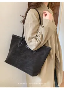 Close-up detail view of a stylish black suede tote bag worn by a model gracefully.
