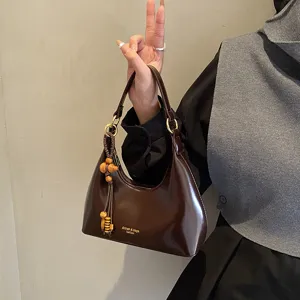 Close-up detail of the vintage brown underarm hobo bag with wooden bead tassel pendant.